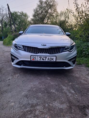Kia: Автомобиль Kia серебристого цвета. Седан с выразительной решеткой