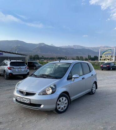 продажа авто в кыргызстане: Серебристый хэтчбек Honda Fit, представленный на изображении, является