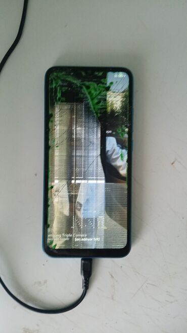Ekranı zədələnmiş, lakin işlək vəziyyətdə olan smartfon. Cihaz şarj