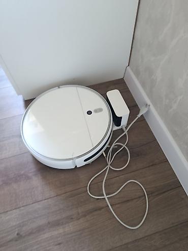 Ağıllı robot tozsoran – dairəvi korpuslu, ağ rəngdə. Şarj stansiyası