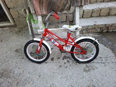 tutacaqlı üçtəkərli velosiped: Təkərləri ağ haşiyəli, qırmızı rəngli uşaq velosipedi. Ağ