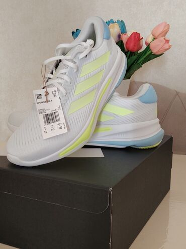 kişi üçün ev şap şapları: Adidas Supernova Base M modeli, ağ rəngdə, sarı və mavi detallarla