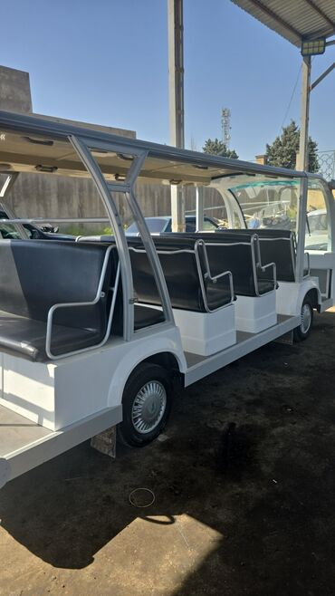 Ağ rəngdə, uzun gövdəli elektrikli sərnişin daşıma avtobusu. Nəqliyyat