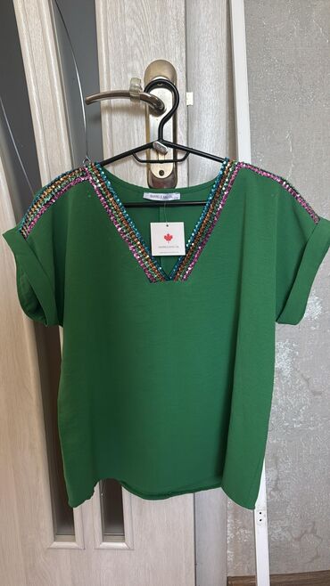 orus koynekler: Yaşıl rəngdə qısaqol qadın bluzu. Bluzanın V-yaxası və çiyin hissələri