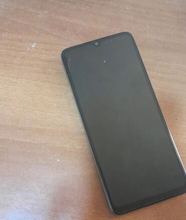 Tünd yaşıl rəngdə Redmi smartfon, arxa hissəsində böyük dairəvi kamera