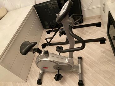 Elliptik trenajorlar: Gümüşü rəngdə olan stasionar velosiped. Məşq zamanı rahatlıq üçün