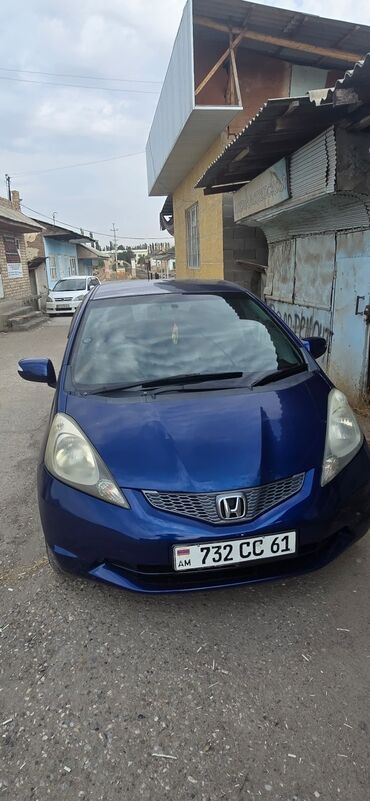 мини электромобиль: Синий хэтчбек Honda Fit с передним приводом, оснащенный бензиновым