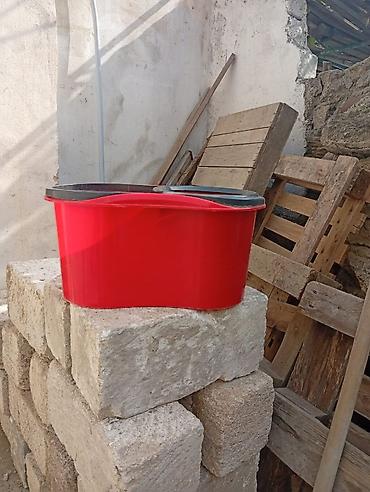 Qırmızı rəngli döşəmə silmə vedrəsi, sıxma bölməsi ilə. Plastik