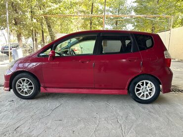 купить маленькую машину недорого: Хэтчбек Honda Fit в красном цвете. Модель оснащена 5 дверями, что