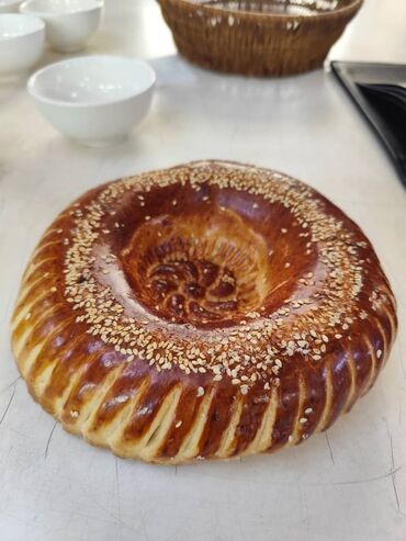 Выпечка, хлебобулочные изделия: Свежеиспеченный узбекский хлеб круглой формы, украшенный характерными — 2