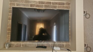 işlenmiş tv: LG televizoru, divara bərkidilmiş. Qara rəngdədir və müasir dizaynı