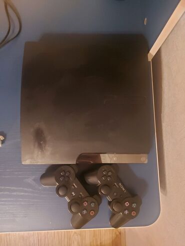 rol oyun konsolu: Qara rəngdə olan Sony PlayStation 3 oyun konsolu. İki ədəd Sony