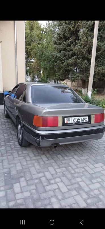 фары на поло: Седан Audi 100 серого цвета. Автомобиль оснащен четырьмя дверями и