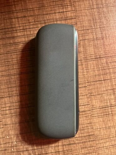 iqos iluma qiymeti: Qara rəngli, yığcam dizaynlı IQOS cihazı. Cibdə və ya çantada