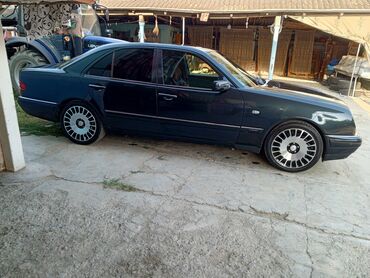 qoşqusu olan avtomobil: Mercedes-Benz E-Class sedan tünd boz rəngdədir. Avtomobilin qabaq və