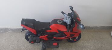 Qırmızı və qara rənglərdə olan uşaq elektrik motosikleti. Uşaqların