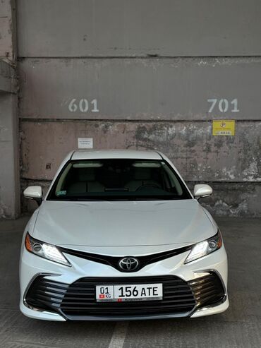 машины 2010 года и выше: Белый седан Toyota Camry, оснащенный светодиодными фарами и дневными