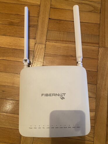Modemlər və şəbəkə avadanlıqları: Ağ rəngli Fibernet simsiz router. İki antenası var. Evdə və ya ofisdə