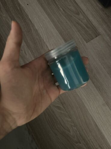 Şəffaf qapaqlı kiçik bir bankada mavi rəngli slime. Bu yapışqan maye