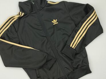 reserwed kurtki zimowe: Czarna kurtka sportowa marki Adidas, ozdobiona złotymi trzema paskami