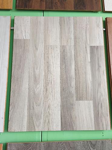 laminant: Açıq boz-bej tonlarında, palıd teksturalı laminat döşəmə paneli. - — 1