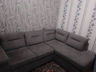 Künc divan, boz rəngdə və müasir dizaynda. Qonaq otağı üçün uyğun olan