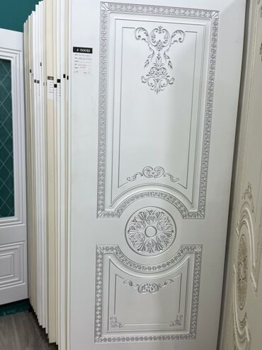 ev qaplsl: Ağ rəngdə, üzərində bəzək elementləri olan qapı. Qapının yuxarı