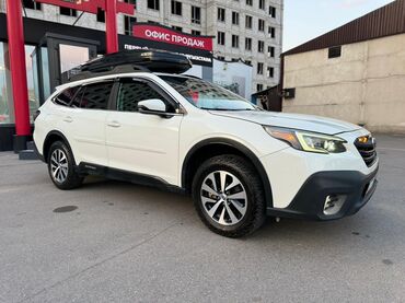 кофр на крышу автомобиля: Белый кроссовер Subaru Outback с установленным на крыше грузовым