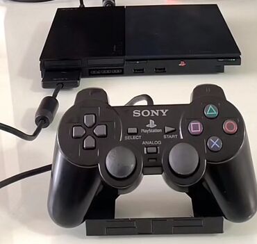 PS2 & PS1 (Sony PlayStation 2 & 1): Qara rəngdə olan Sony PlayStation 2 oyun konsolu. Kompakt dizaynı və