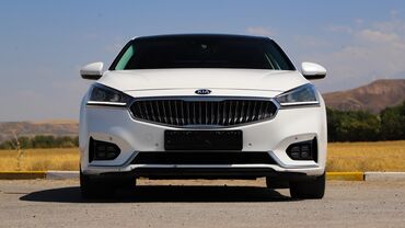 кара электро: Белый седан Kia K7 с динамичным дизайном и характерной решеткой