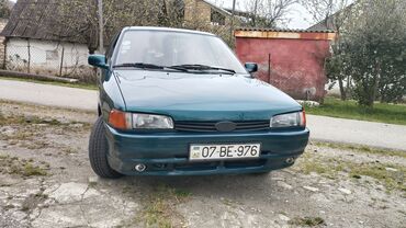 авто фольксваген поло: Tünd yaşıl rəngli dördqapılı Mazda 323 sedan avtomobili. Avtomobilin