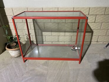Полочные витрины: Bu vitrin şüşə yan panellərə və qırmızı rəngli metal çərçivəyə