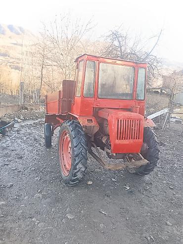 Qırmızı rəngli yığcam kənd təsərrüfatı traktoru, arxada yük daşımaq