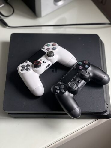 playstation oyunları: Qara rəngli PlayStation 4 oyun konsolu və iki ədəd idarəetmə pultu –