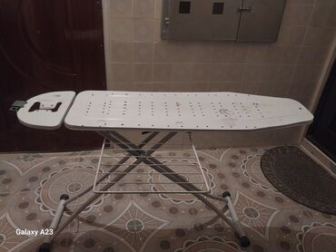 ayaqlı lövhə: Ağ rəngdə, metal ayaqlı, qatlana bilən ütü masası. Masanın səthi ütü