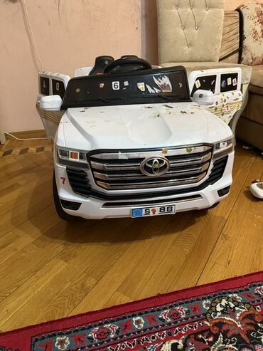 Ağ rəngli uşaq elektrikli avtomobili. Avtomobilin ön hissəsində