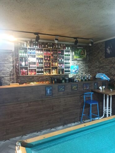 Sifarişlə restoran stulları: Şəkil bar sahəsini, onun şüşələrlə dolu rəfləri və bar tezgahını əks