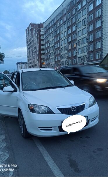 арзан авто: Белый седан Mazda Demio. Компактный автомобиль удобен для города, не