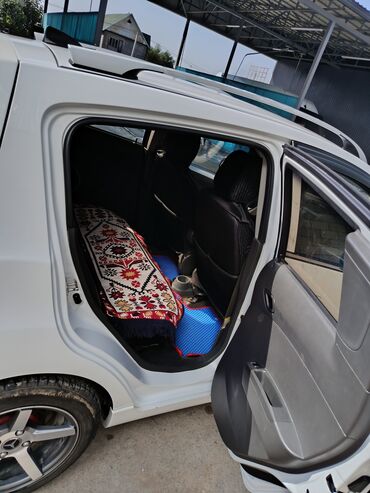маленькая машина: Белый хэтчбек Chevrolet Spark с пятидверным кузовом. Автомобиль