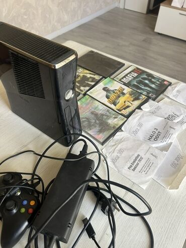 xbox 360 qiymeti: Qara rəngdə olan Xbox 360 oyun konsolu, bir ədəd idarəetmə pultu