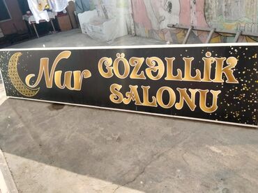 Reklam lövhələri: Qara fonda qızılı rəngdə "Nur Gözəllik Salonu" yazısı olan reklam