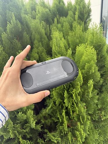 ps disk: Sony PS Vita portativ oyun konsolu. Şəkillərdə qara rəngli cihaz və PS — 2
