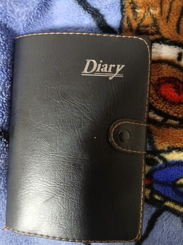 stul uzlukleri qiymetleri: Qara rəngdə, dəri üzlüklü gündəlik. Gündəliyin üzərində "Diary" sözü