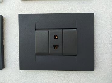 tek guzgu: Qara rəngdə, divara quraşdırılan elektrik rozetkası və iki ədəd açarı