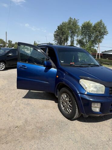 хорошая качественная обувь: Синий кроссовер Toyota RAV4 с рейлингами на крыше и дефлекторами на