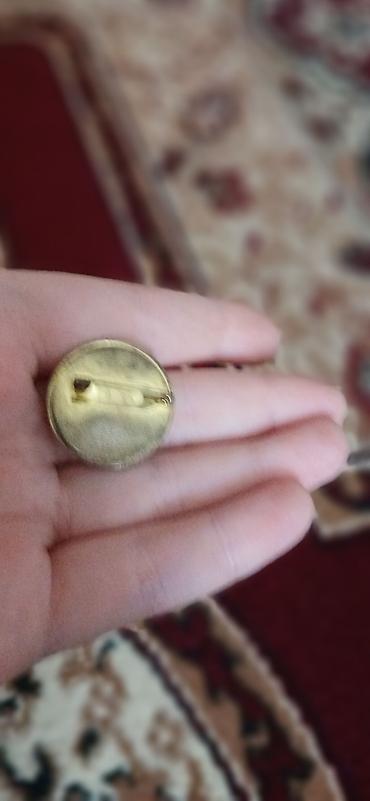 papaq sekilleri: Rəngli nişan/pin – dairəvi, metal əsaslı. - Ön tərəf: ağ fonda — 1