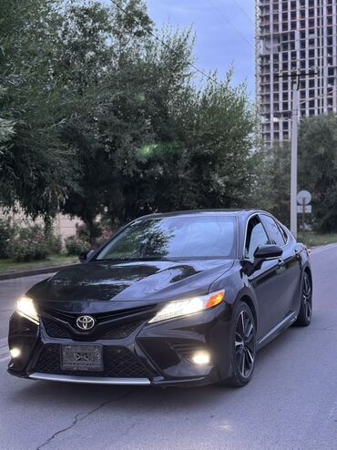 Toyota: Черный седан Toyota Camry. Автомобиль оснащен стильными колесными