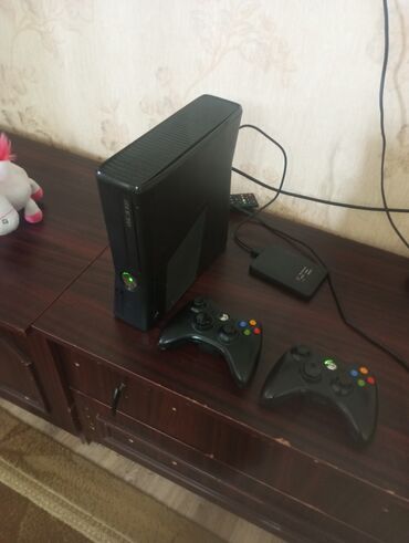 xbox 360 oyunlari: Qara rəngdə olan Xbox 360 oyun konsolu. İki ədəd simsiz oyun idarəetmə