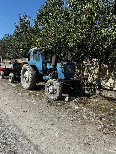 Mavi rəngli təkərli kənd təsərrüfatı traktoru və qoşqu