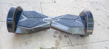 Samokatlar: Qara rəngli, iki təkərli, özübalanslı hoverboard. Üzərindəki
